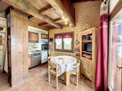 a kitchen with a table in a room with wooden walls at Charmant duplex près du téléski du Bouchet, idéal pour famille - FR-1-560-11 in Combloux