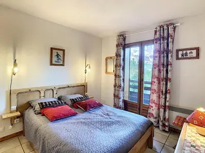 a bedroom with a bed with two pillows and a window at Appartement cosy 2 pièces à 2 pas des remontées mécaniques de Combloux - FR-1-560-20 in Combloux