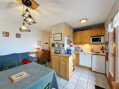 a kitchen with wooden cabinets and a table with a tablecloth on a table sidx at Appartement cosy 2 pièces à 2 pas des remontées mécaniques de Combloux - FR-1-560-20 in Combloux