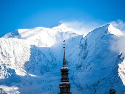 a snow covered mountain with a clock tower in the foreground at Appartement cosy 2 pièces à 2 pas des remontées mécaniques de Combloux - FR-1-560-20 in Combloux