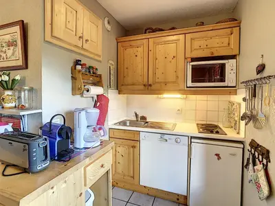 a kitchen with wooden cabinets and a white appliance at Appartement cosy 2 pièces à 2 pas des remontées mécaniques de Combloux - FR-1-560-20 in Combloux