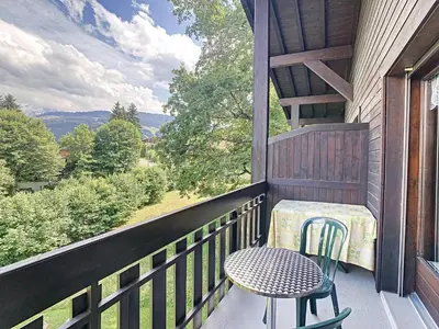 a table and chair on a balcony with a view at Duplex cosy 35m² près du centre de Combloux, face au Mont Blanc - FR-1-560-19 in Combloux