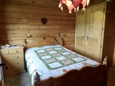a bedroom with a bed and a wooden wall at Grand chalet confortable à Demi-Quartier, 13 couchages - FR-1-560-36 in Demi-Quartier