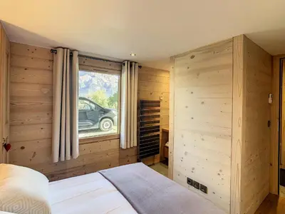 a bedroom with wooden walls and a bed with a window at Appartement 4P avec terrasse et vue Mont Blanc - FR-1-560-24 in Combloux