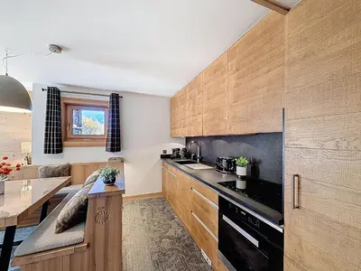 a kitchen with wooden cabinets and a wooden table at Appartement 4P avec terrasse et vue Mont Blanc - FR-1-560-24 in Combloux