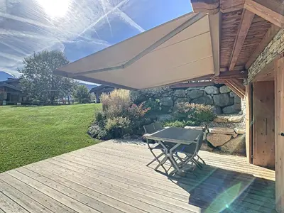 a patio with a table and chairs on a deck at Appartement 4P avec terrasse et vue Mont Blanc - FR-1-560-24 in Combloux