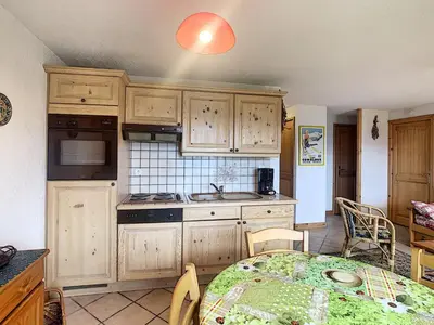 a kitchen with wooden cabinets and a table with a tablecloth at Charmant 2 pièces cabine avec jardin, près de Combloux - FR-1-560-33 in Combloux
