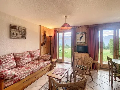 a living room with a couch and a tv and a table at Charmant 2 pièces cabine avec jardin, près de Combloux - FR-1-560-33 in Combloux