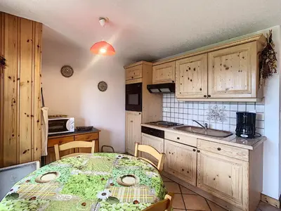 a kitchen with a table and a kitchen with wooden cabinets at Charmant 2 pièces cabine avec jardin, près de Combloux - FR-1-560-33 in Combloux