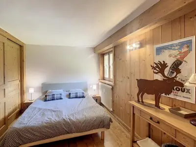 a bedroom with a bed and a wooden wall at 3 pièces, piscine intérieure, parking, proche centre à Combloux - FR-1-560-27 in Combloux