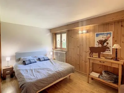 a bedroom with a bed and a wooden wall at 3 pièces, piscine intérieure, parking, proche centre à Combloux - FR-1-560-27 in Combloux