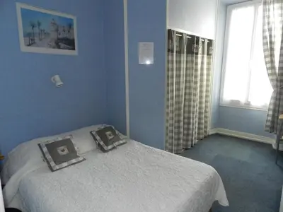 a blue bedroom with a bed with two diplomas on it at Hotel du Mont Blanc in Sallanches