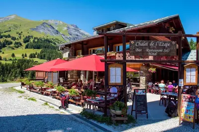 a restaurant with tables and umbrellas in front of a building at Chalet-Hôtel de l'Etape in Les Contamines-Montjoie