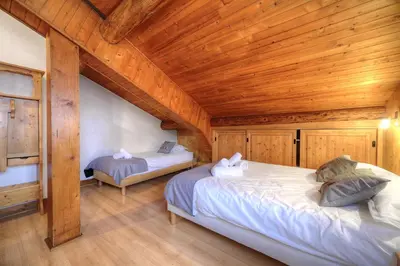 two beds in a room with a wooden ceiling at Chalet-Hôtel de l'Etape in Les Contamines-Montjoie