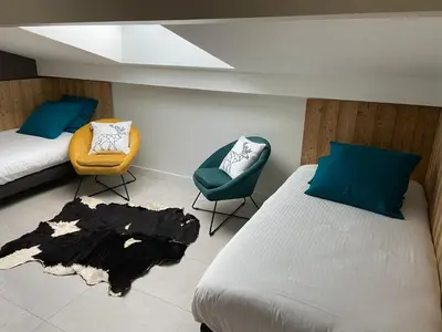 a bedroom with two beds and a chair and a rug at Chalet Pleine Vue & Spa in Chamonix-Mont-Blanc