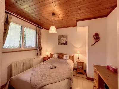 a bedroom with a bed in a room with wooden ceilings at Bel Apt au Centre de Combloux avec Jardin, Balcon, Wifi et Parking à 300m des Commerces - FR-1-560-52 in Combloux