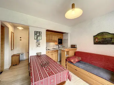 a room with a red couch and a kitchen at Appartement cosy au pied des pistes à Combloux avec balcon et casier à skis - FR-1-560-61 in Combloux