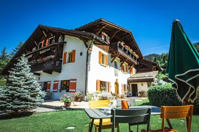 a house with a table and chairs in the yard at Chalet-hôtel Gai Soleil in Les Contamines-Montjoie