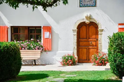 a house with a wooden door and flowers in front of it at Chalet-hôtel Gai Soleil in Les Contamines-Montjoie