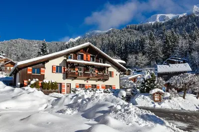 a snow covered house with a balcony in the snow at Chalet-hôtel Gai Soleil in Les Contamines-Montjoie