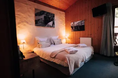 a bedroom with a bed in a room with wooden walls at Chalet-hôtel Gai Soleil in Les Contamines-Montjoie