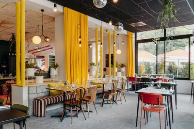 a restaurant with tables and chairs and yellow curtains at PlanB - Living Saint-Gervais - 250m des Remontées Mécaniques in Saint-Gervais-les-Bains
