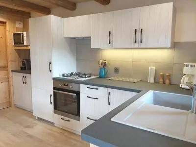 a kitchen with white cabinets and a sink at Le Granit in Combloux
