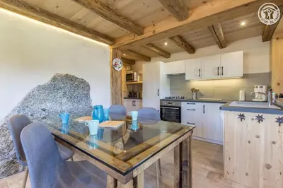 a kitchen and dining room with a glass table and chairs at Le Granit in Combloux
