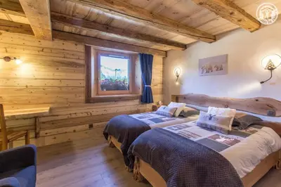 two beds in a room with wooden walls at Le Granit in Combloux