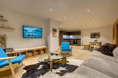 a living room with a couch and a tv on the wall at Residence Le Green in Chamonix-Mont-Blanc