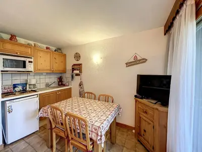 a kitchen with a table with chairs and a table and a television at Studio cabine proche centre Combloux, 4 pers, balcon, parking - FR-1-560-53 in Combloux