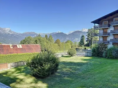a yard with a house with mountains in the background at Studio cabine proche centre Combloux, 4 pers, balcon, parking - FR-1-560-53 in Combloux