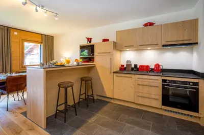a kitchen with wooden cabinets and a table and chairs at Coin des Drus Apartment - Chamonix All Year in Chamonix-Mont-Blanc