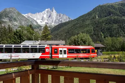 a red and white train on the tracks with mountains at Coin des Drus Apartment - Chamonix All Year in Chamonix-Mont-Blanc