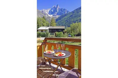 a table on a deck with a view of a mountain at Coin des Drus Apartment - Chamonix All Year in Chamonix-Mont-Blanc