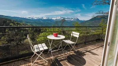 a table and two chairs on a balcony with mountains at Gite74, GLMB à 3 min de l'ascenseur des Thermes in Saint-Gervais-les-Bains