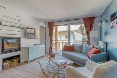 a living room with a blue couch and a fireplace at Rare ! Appartement rénové dans le centre piéton de Megève in Megève