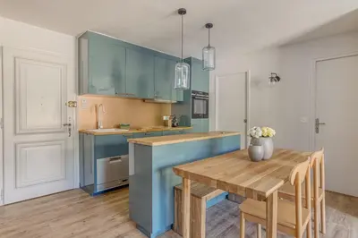 a kitchen with blue cabinets and a wooden table at Rare ! Appartement rénové dans le centre piéton de Megève in Megève