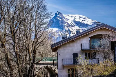 a house with a snow covered mountain in the background at Ski in ski out Le Moulin charming duplex just 50 m from Princesse gondola Megève in Demi-Quartier