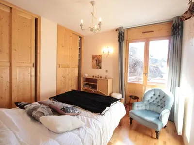 a bedroom with a bed and a blue chair at Appartement 3 chambres, 2 sdb, parking, proche pistes, équipements de standing - FR-1-572-46 in Les Carroz d'Araches