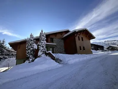 a house covered in snow in front of a road at Appartement 3 chambres, 2 sdb, parking, proche pistes, équipements de standing - FR-1-572-46 in Les Carroz d'Araches