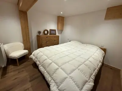 a bedroom with a large white bed and a chair at Chalet équipé avec poêle et garage, proche centre et remontées mécaniques - FR-1-572-107 in Les Carroz d'Araches