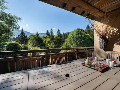 a wooden table on a deck with a view at Chalet familial à Megève avec piscine et sauna pour 12 personnes - FR-1-569-2 in Megève