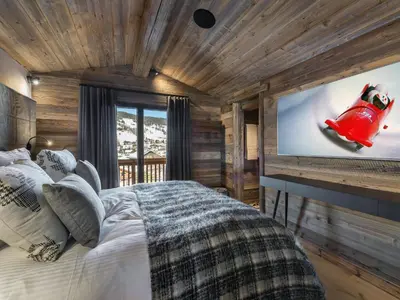 a bedroom with a bed and a large screen tv at Chalet de luxe avec jacuzzi, salle cinéma et piscine au centre de Megève - FR-1-569-10 in Megève