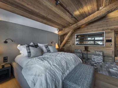 a bedroom with a large bed and a wooden ceiling at Chalet de luxe avec jacuzzi, salle cinéma et piscine au centre de Megève - FR-1-569-10 in Megève