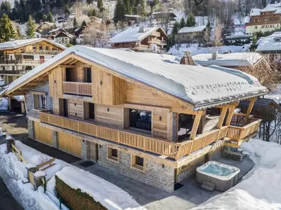 a log home in the snow with a snow covered roof at Chalet de luxe avec jacuzzi, salle cinéma et piscine au centre de Megève - FR-1-569-10 in Megève