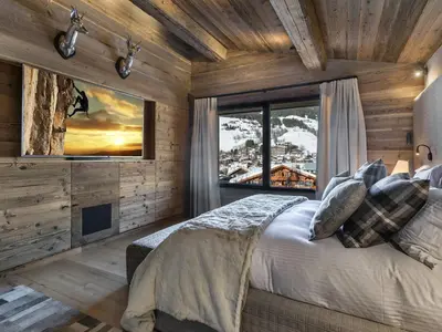 a bedroom with a bed and a large window at Chalet de luxe avec jacuzzi, salle cinéma et piscine au centre de Megève - FR-1-569-10 in Megève