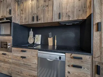 a kitchen with wooden cabinets and a stainless steel dishwasher at Charmant appartement au Mont d'Arbois proche pistes, parking inclus - FR-1-569-11 in Megève