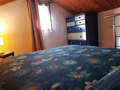 a bedroom with a bed with a blue blanket with flowers at Petit chalet savoyard in Domancy