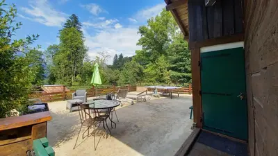 a patio with a table and chairs and a green door at Petit chalet savoyard in Domancy